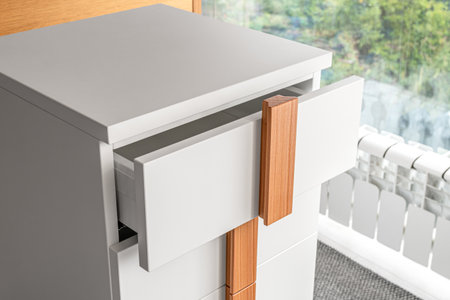Stylish white office commode with wooden handles and legs with open empty drawers closeup view. Comfortable furniture for home and office furnishingの写真素材