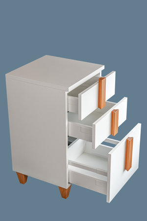 Stylish white office commode with wooden handles and legs with open empty drawers isolated on blue background. Comfortable furniture for home and office furnishingの写真素材