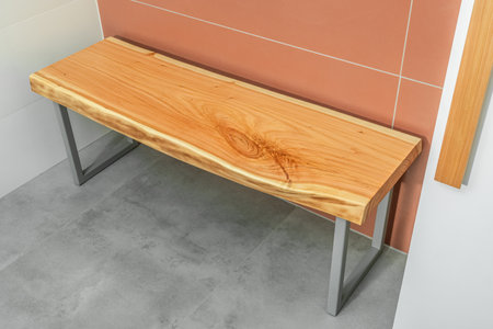 Bench with live edge wood top and gray metal legs in modern design in contemporary bathroom with concrete and terracotta tilesの写真素材