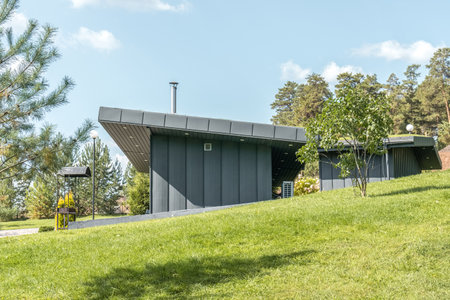 Modern guest house with standing seam facade panoramic glazing and large flat roof overhang in park. Minimalist architectural style of public buildingの写真素材