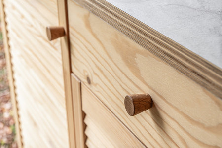 Wooden louvered doors with wooden knob handles close-up. Louvered doors of outdoor kitchen are made from light pine wood with natural grain patternの写真素材