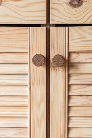 Wooden louvered doors with wooden knob handles close-up. Louvered doors of outdoor kitchen are made from light pine wood with natural grain patternの写真素材