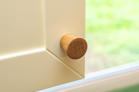 Wooden handle attached to yellow sleek kitchen cabinet with a simple design. Solid oak cabinet knob close up viewの写真素材