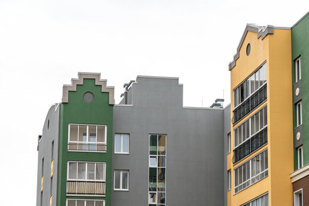 Buildings with green, gray, and yellow walls, decorative facades, large windows, balconies, and a bright sky background. Urban architecture conceptの写真素材