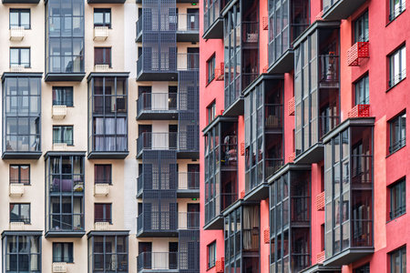 Contemporary apartment buildings with beige and red facades, featuring numerous balconies with dark-framed windows. Urban housing conceptの写真素材