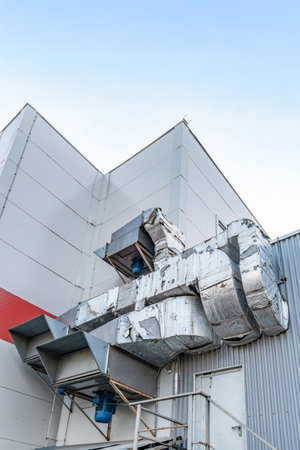 Large insulated ventilation ducts and industrial fans attached to a metal building wall, concept of air circulation systemの写真素材