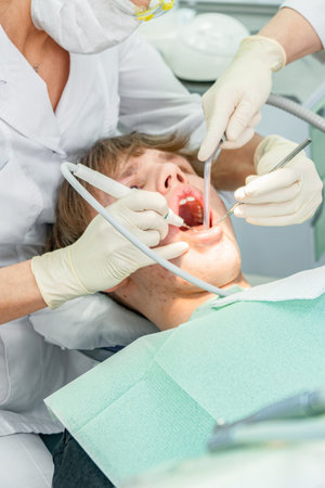Teenager undergoes dental procedures in a bright clinic with professionals attending to oral health needsの写真素材