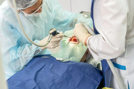 Two dental professionals perform a procedure on a patient in a clinical environment, focused and attentive to detailsの写真素材