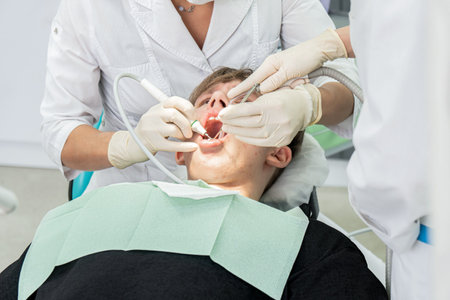 Teenager undergoes dental procedures in a bright clinic with professionals attending to oral health needsの写真素材