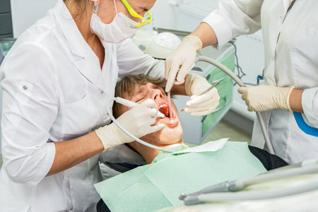 Teenager undergoes dental procedures in a bright clinic with professionals attending to oral health needsの写真素材