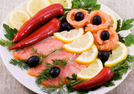 Red fish, lemon, olives on plateの写真素材