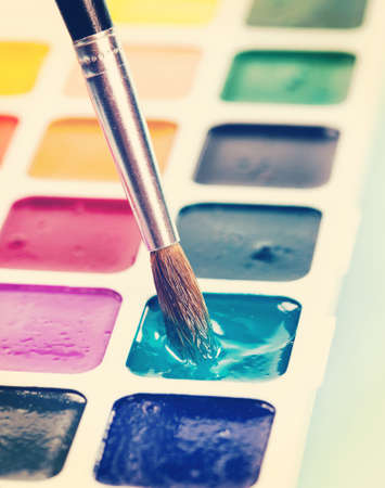 Watercolor paints and brush on the table. Vintage retro hipster style versionの写真素材