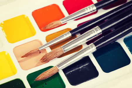 Watercolor paints and brush on the table. Vintage retro hipster style version