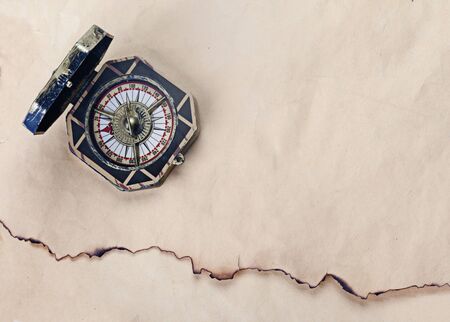 Antique compass over old paper background