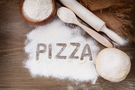 The pizza inscription by flour on the wooden boardの写真素材