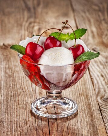 Ice cream with fruits and cherries on old boardの写真素材