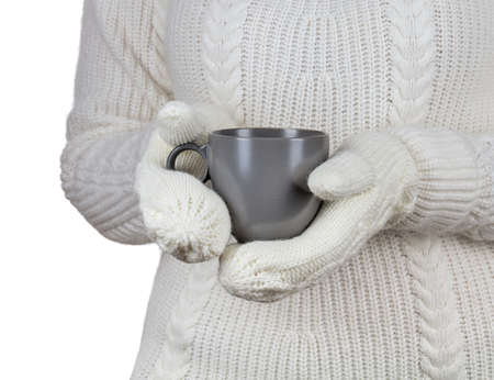 Christmas concept. Coffee cup in female hands dressed in mittens.の写真素材