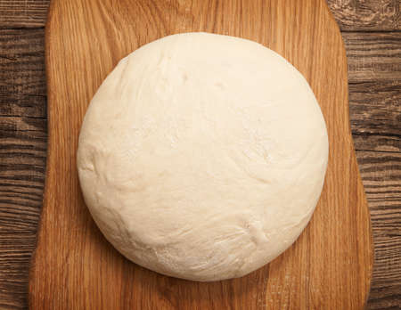top view fresh raw dough for pizza or bread baking on wooden cutting boardの写真素材