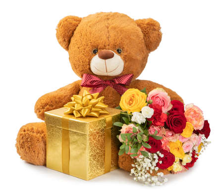 teddy bear gold gift and a bouquet of flowers on a white backgroundの写真素材
