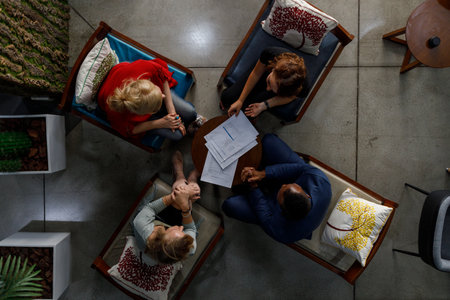Directly above shot of diverse professional partners with contract papers on table discussing agreement terms in meeting at officeの写真素材