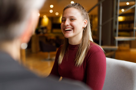 Portrait of confident beautiful young female employee laughing in meeting at officeの写真素材