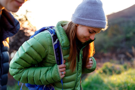 Portrait of female hiker in winter clothes looking down while hiking up the mountain with her friend...