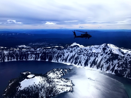 An attack helicopter flies over a mountain lake in Oregon.の写真素材
