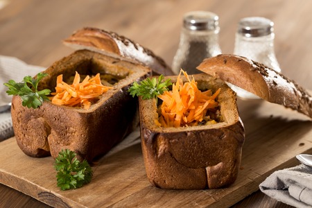 Fresh pea soup in a Bread Bowl, on a wooden board with salt and papperの写真素材