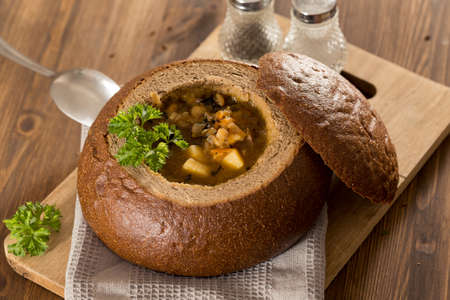 Fresh pea soup in a Bread Bowl, on a wooden board with salt and papper
