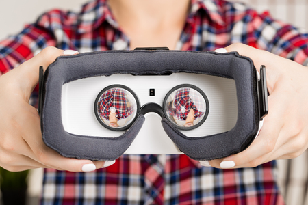 Happy woman getting experience using VR-headset glasses of virtual reality at home much gesticulating handsの写真素材