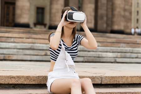 Young girl sitting on the stairs, near the university, in virtual reality in VRの写真素材