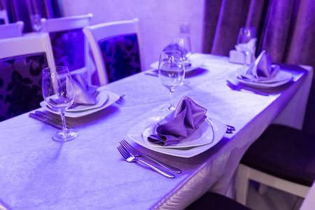 Empty glasses and dishes set in an empty interior new luxury restaurant with covered tables and crockeryの写真素材