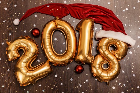 Bright gold balloons figures 2018, New Year Balloons with glitter stars on dark wood table background. Christmas and new year celebrationの写真素材