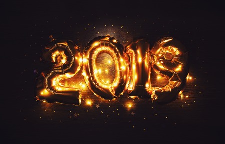 Bright metallic gold balloons figures 2019, Christmas, New Year Balloon with glitter stars on dark wood table backgroundの写真素材