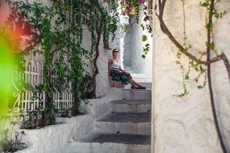 Tourist Girl on Beautiful Streets of old Marmaris. Narrow streets with stairs among the houses with white brick, green plants and flowers in the old town of resort of in Turkeyの写真素材