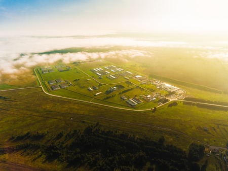 Panoramic aerial view of working factory. Aerial view through the clouds at working factory. Concept of buildings at the factory, giants pipesの写真素材