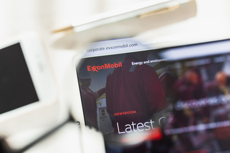 Los Angeles, California, USA - 27 February 2019: Exxon Mobil Corporation official website homepage under magnifying glass. Exxon Mobil Corporation logo visible on smartphone, tablet screenのeditorial素材