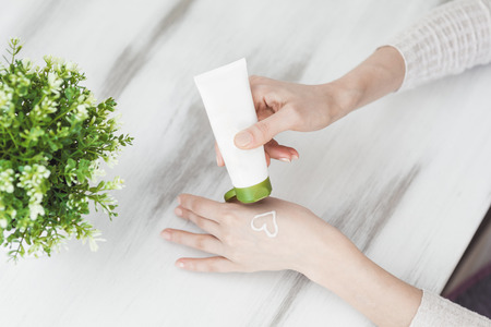 Makeup remove skin care. Closeup woman holding cotton swab and makeup remover liquid cosmetic in hands. Woman cleaning her face with lotion and cotton padの写真素材