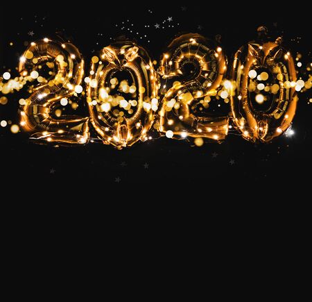 Happy New year 2020 celebration. Bright gold balloons figures, New Year Balloons with glitter stars on dark background. Christmas and new year celebration. Gold foil balloons 2020の写真素材
