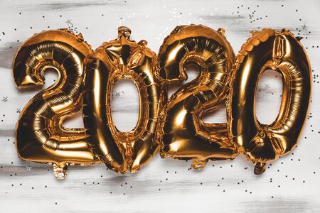 Happy New year 2020 celebration. Bright gold balloons figures, New Year Balloons with glitter stars on wood white background. Christmas and new year celebration. Gold foil balloons 2020の写真素材