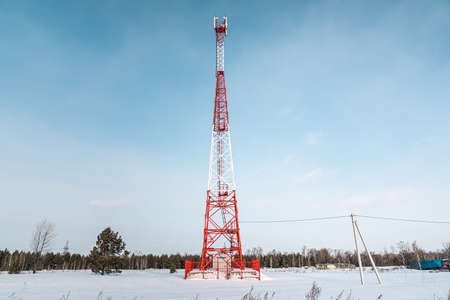 New telecommunication antenna on background of blue sky in the forest winter. Satellite dish telecom...