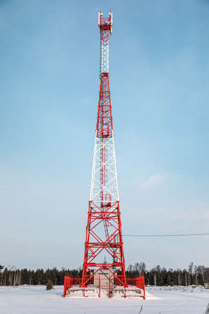 New telecommunication antenna on background of blue sky in the forest winter. Satellite dish telecom...
