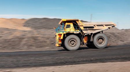 Large quarry dump truck. Big yellow mining truck at work site. Loading coal into body truck....