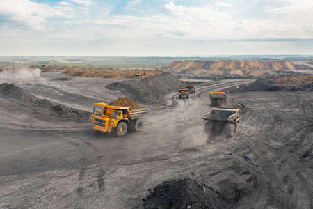 Large quarry dump truck. Big yellow mining truck at work site. Loading coal into body truck. Production useful minerals. Mining truck mining machinery to transport coal from open-pit productionの写真素材
