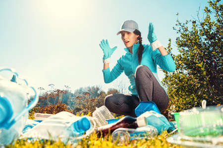 Happy girl holding package for garbage. Young woman volunteer, participates in an environmental campaign and removes plastic garbage in the park. Concept ESG and SDGsの写真素材