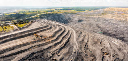 Panoramic aerial view of coal mine. Open pit mine industry, big yellow mining truck for coal quarry....
