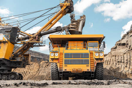Large quarry dump truck. Big yellow mining truck at work site. Loading coal into body truck. Production useful minerals. Mining truck mining machinery to transport coal from open-pit productionの写真素材