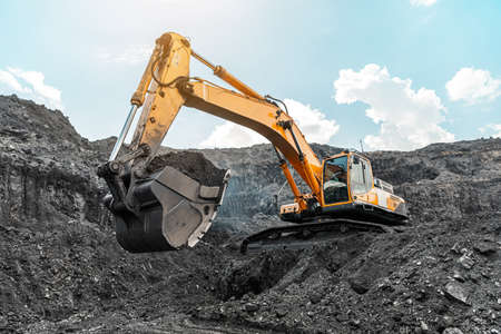 Large quarry dump truck. Big yellow mining truck at work site. Loading coal into body truck. Production useful minerals. Mining truck mining machinery to transport coal from open-pit productionの写真素材