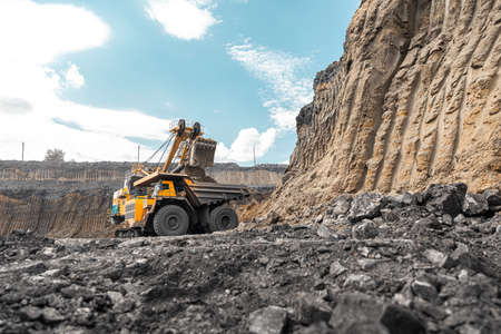 Large quarry dump truck. Big yellow mining truck at work site. Loading coal into body truck. Production useful minerals. Mining truck mining machinery to transport coal from open-pit productionの写真素材