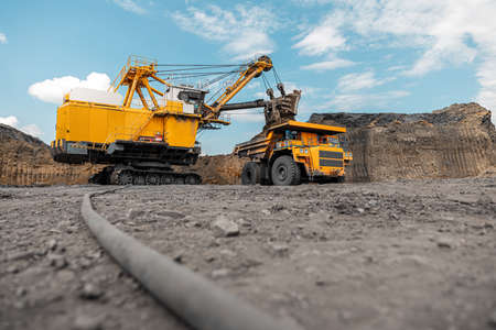 Large quarry dump truck. Big yellow mining truck at work site. Loading coal into body truck....